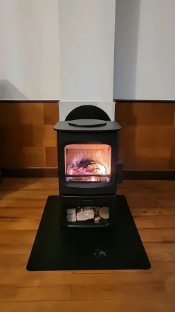 Poêle à bois bûches Charnwood Aire 3 avec base bûcher installé sur une plaque de sol Dixneuf en acier noir