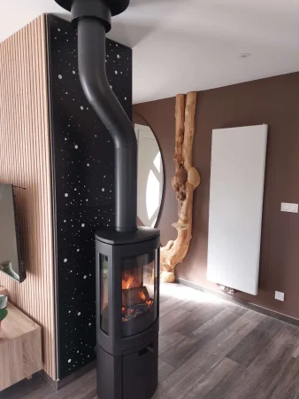 Poêle à bois bûches Jøtul F 378 avec vitres latérales, devant mur avec protections murales au motif "Voie Lactée"