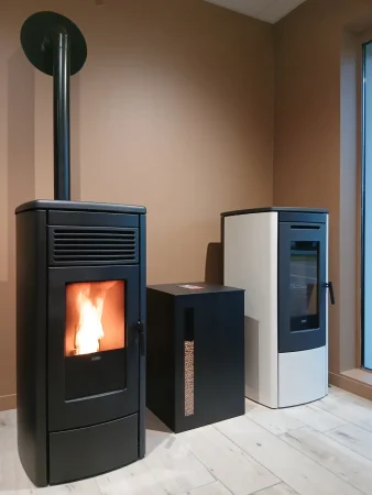 Poêles à granulés de la marque Klover : le modèle Aura 80 noir et le modèle Soft 80 ivoire, avec le stockeur à granulés Titan de Dixneuf