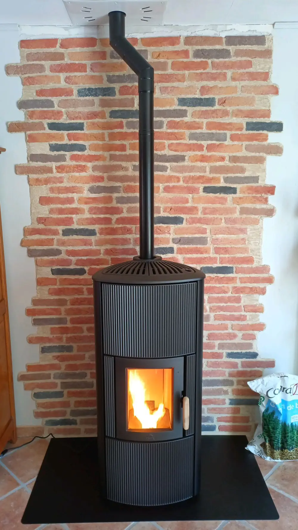 Poêle à granulés Jøtul PF 861 S en fonctionnement, installée sur un plaque de sol en acier noir